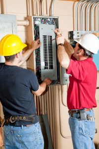 two electricians working with an electrical panel